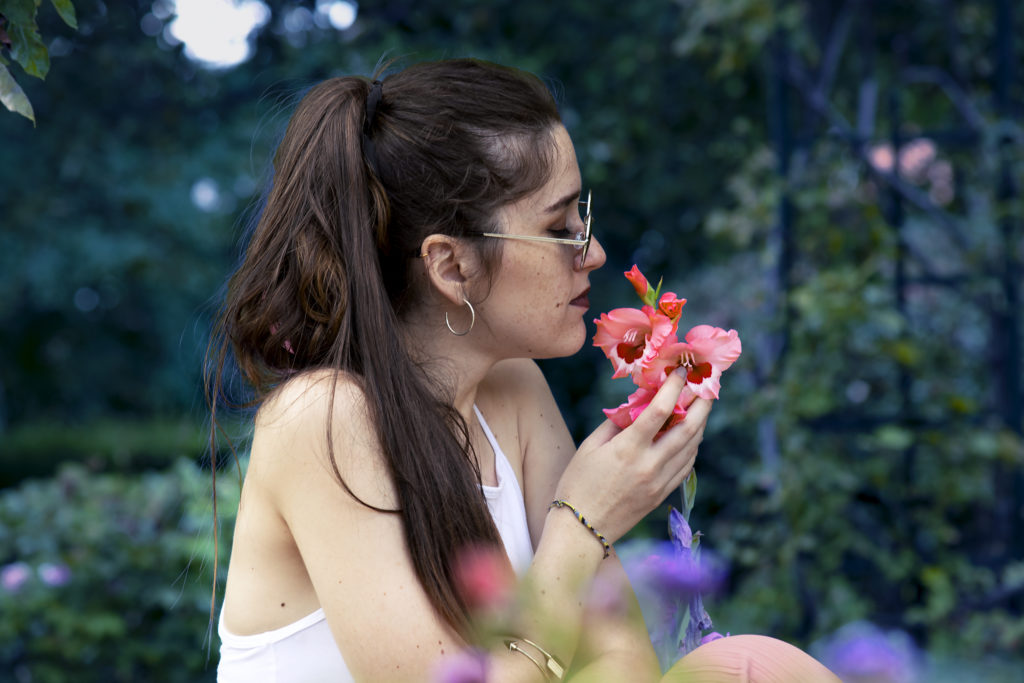 Femme qui renifle une fleur rose