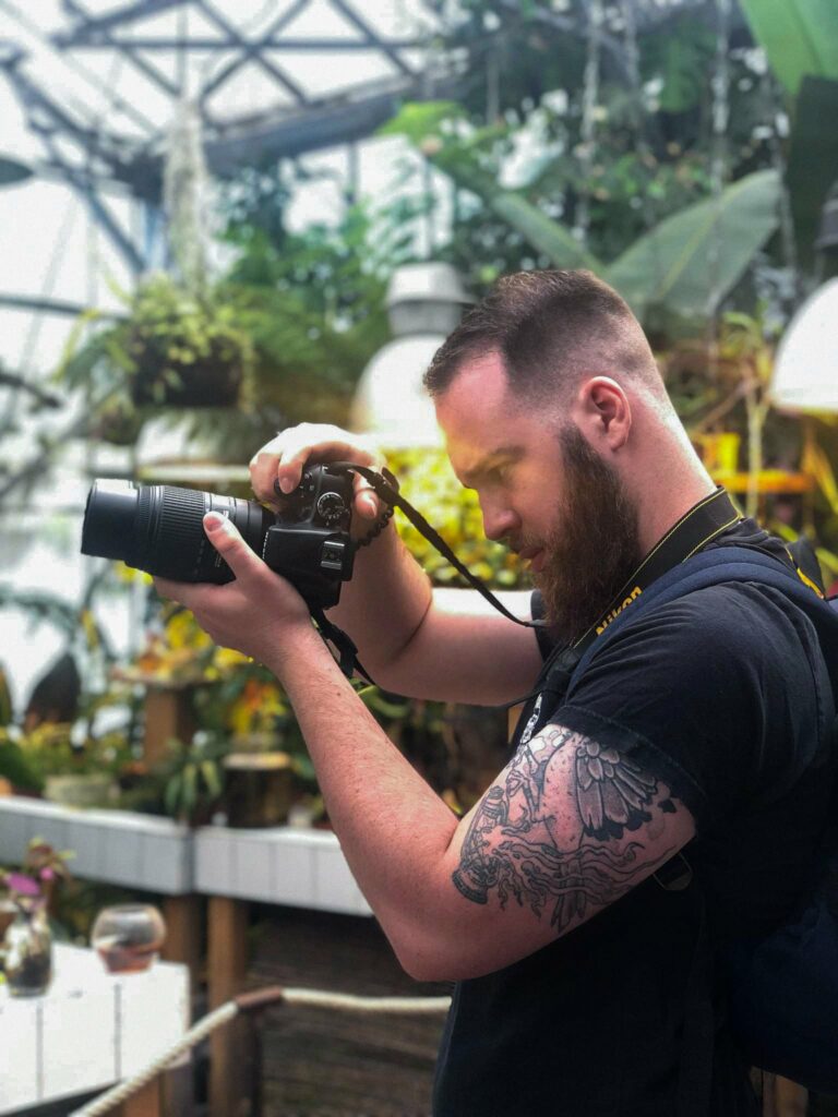 Portrait de Jordan face à des plantes tropicales.